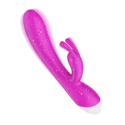 This is a pink adult toy with a smooth, waterproof design. The toy features a main shaft that is slightly curved for internal and G-spot stimulation and a smaller, flexible extension designed for clitoral stimulation. The entire surface is covered with small water droplets, indicating its waterproof capabilities. The base of the toy is white, providing a contrasting accent to the pink shaft. The overall design is ergonomic, easy to hold, and intended to provide dual stimulation for enhanced sexual pleasure.